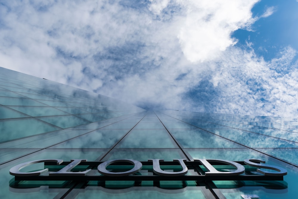 Un primer plano de un edificio de vidrio con nubes en el fondo