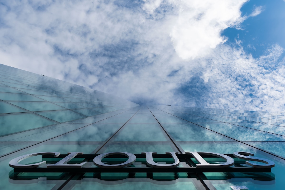 Glasfassade eines Bürogebäudes spiegelt Wolken – Symbolbild für steigende Cloud-Kosten bei Hyperscalern