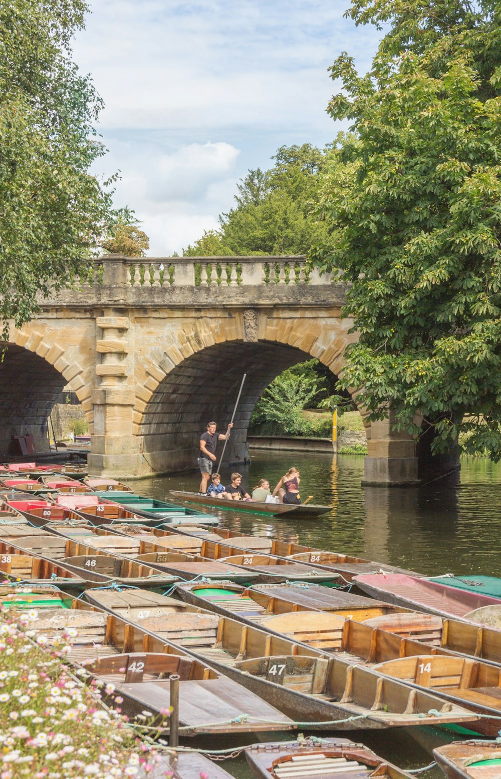 people riding on boat on river under bridge during daytime