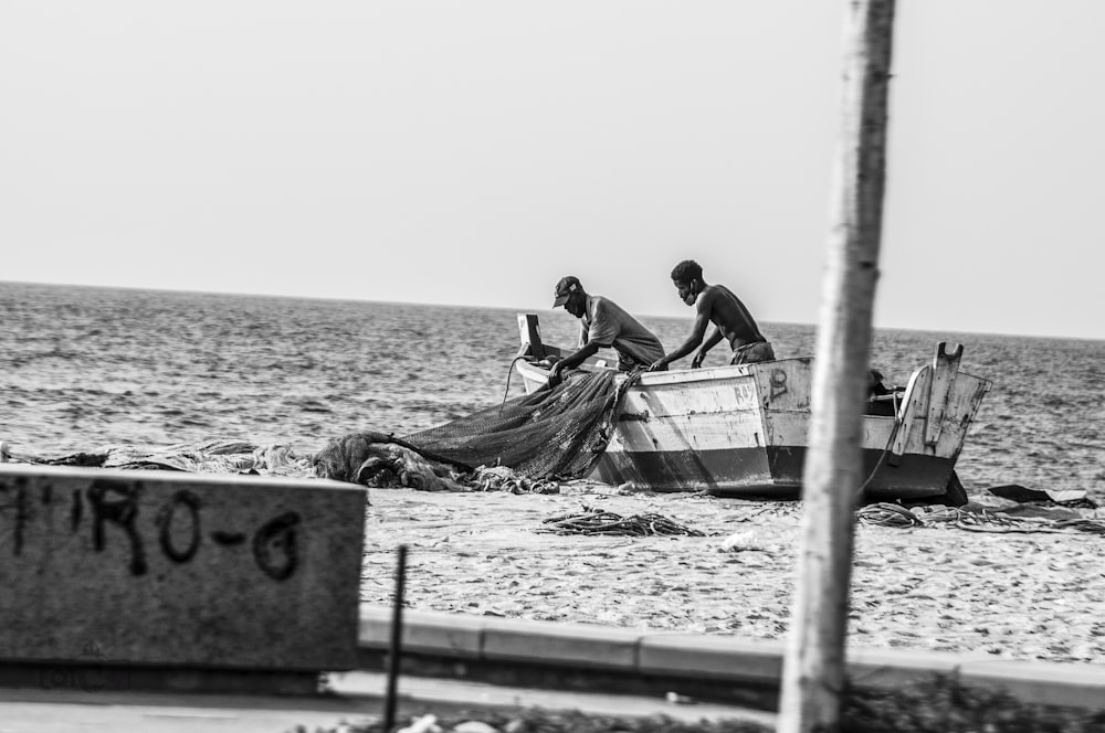 grayscale photo of man and woman sitting on wooden dock