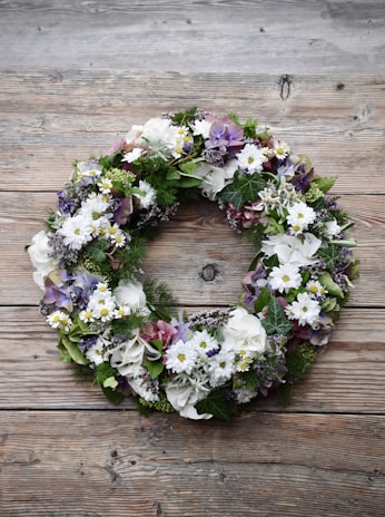 A lush green artificial floral wreath decorated with small blossoms and leaves.