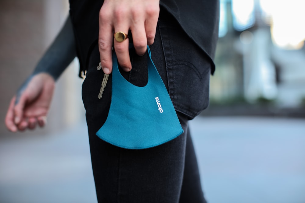 person in black denim jeans holding blue and black bag