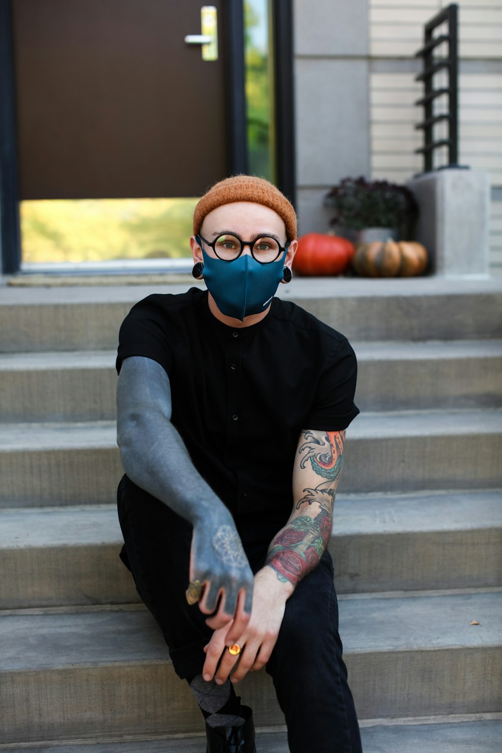 man in black crew neck t-shirt with blue framed sunglasses and blue denim jeans sitting