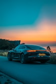 A sleek sports car parked on a winding mountain road at sunset.