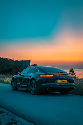 A sleek sports car parked on a winding mountain road at sunset.