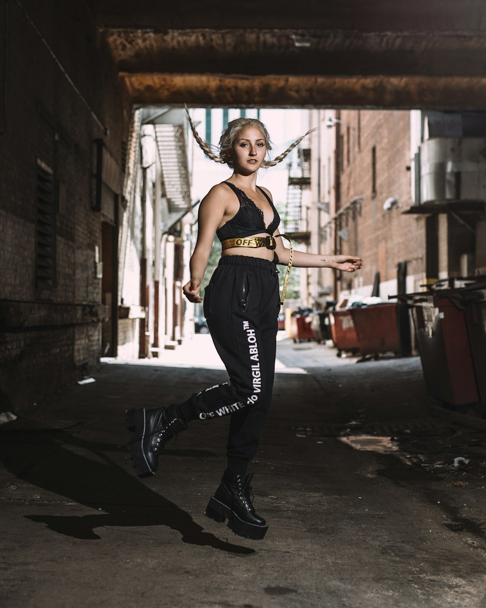 woman in black pants and black leather boots standing on black asphalt road during daytime