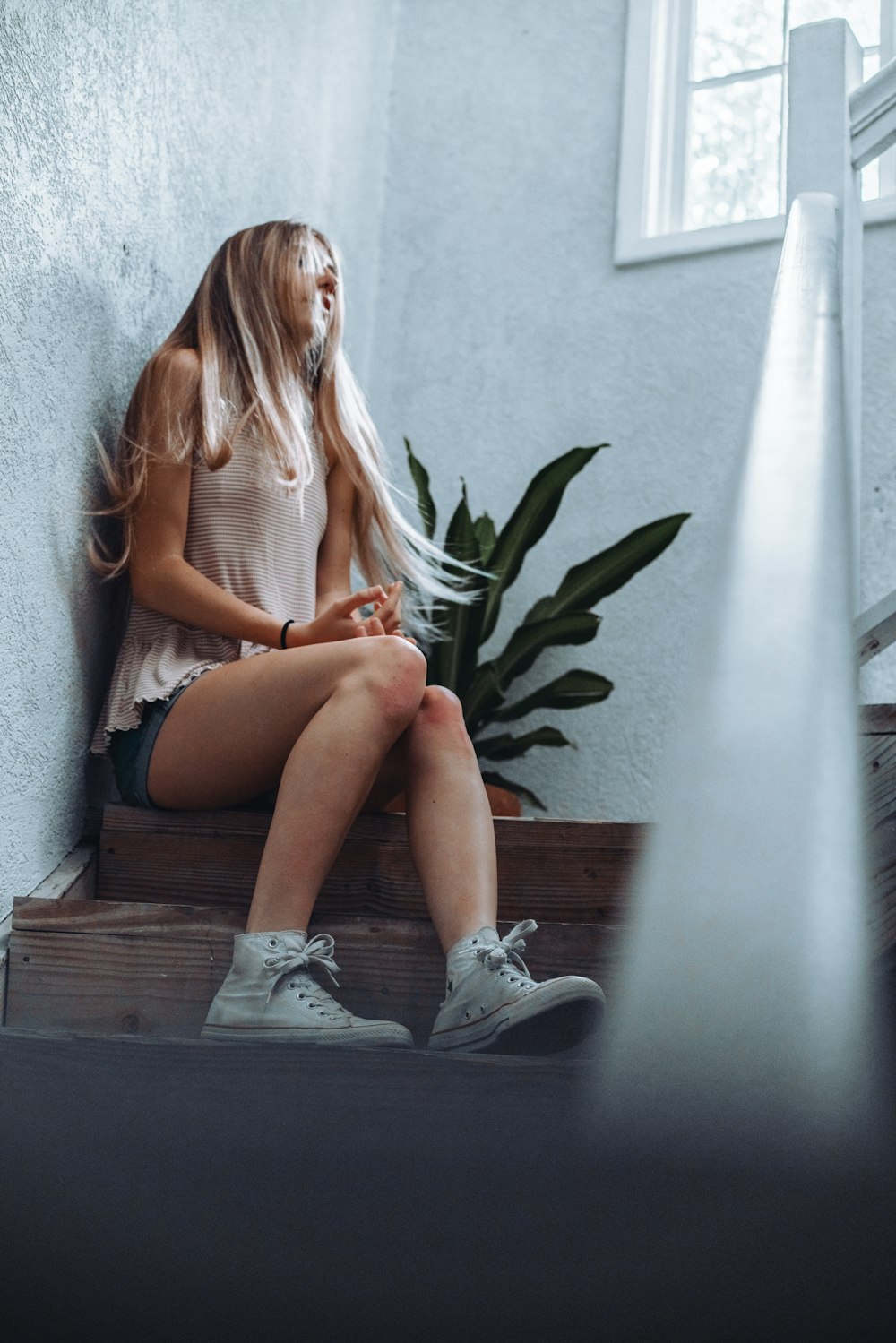 woman in white tank top sitting on brown wooden bench