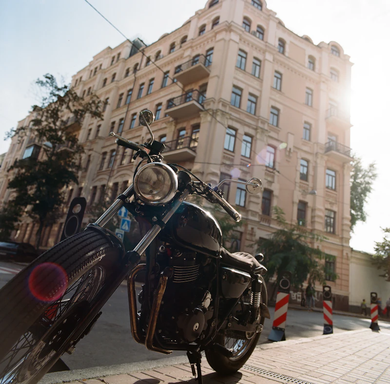 Black motorcycle parked on a sidewalk near a building