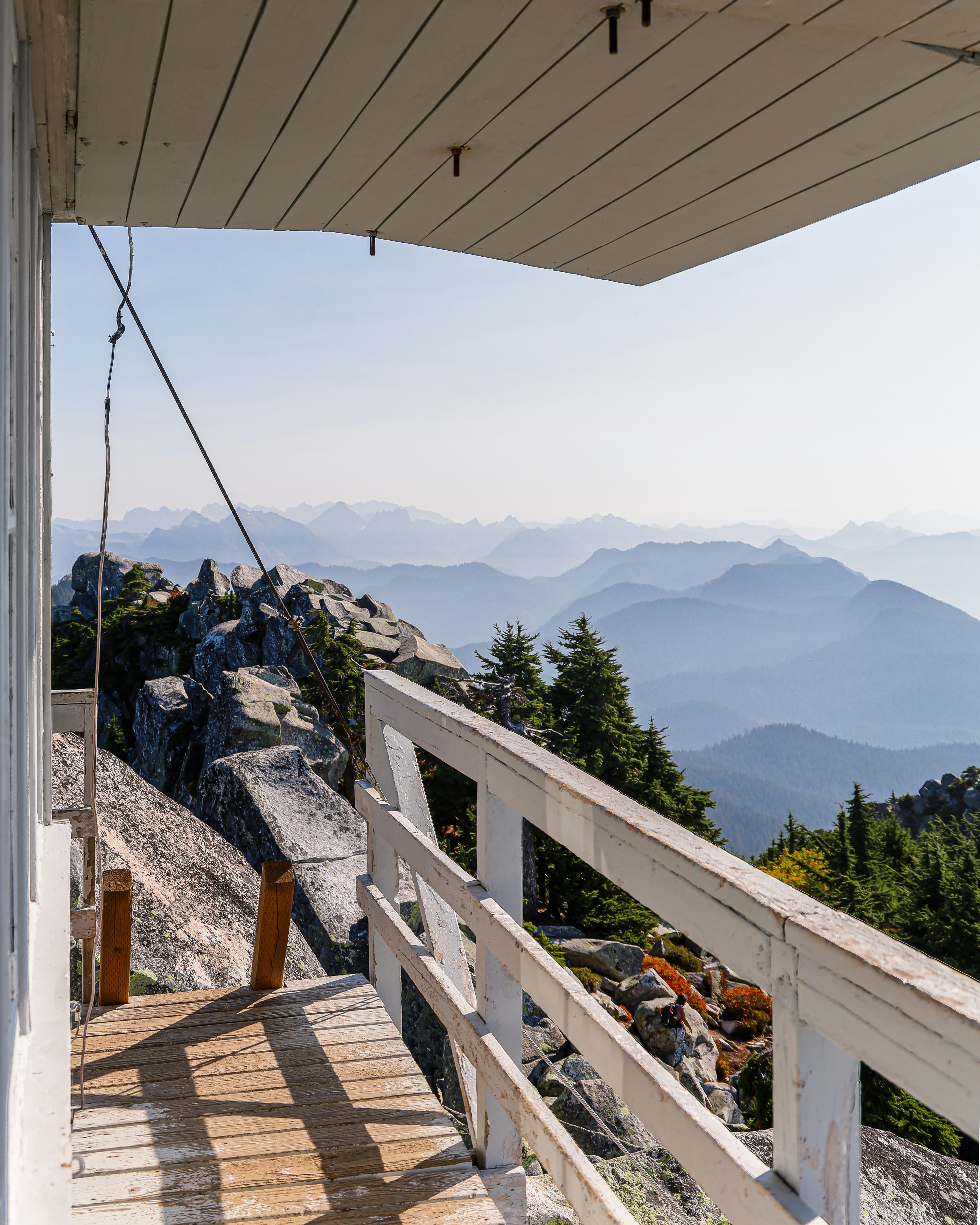brown wooden deck near green trees and mountains during daytimeby Andrew S