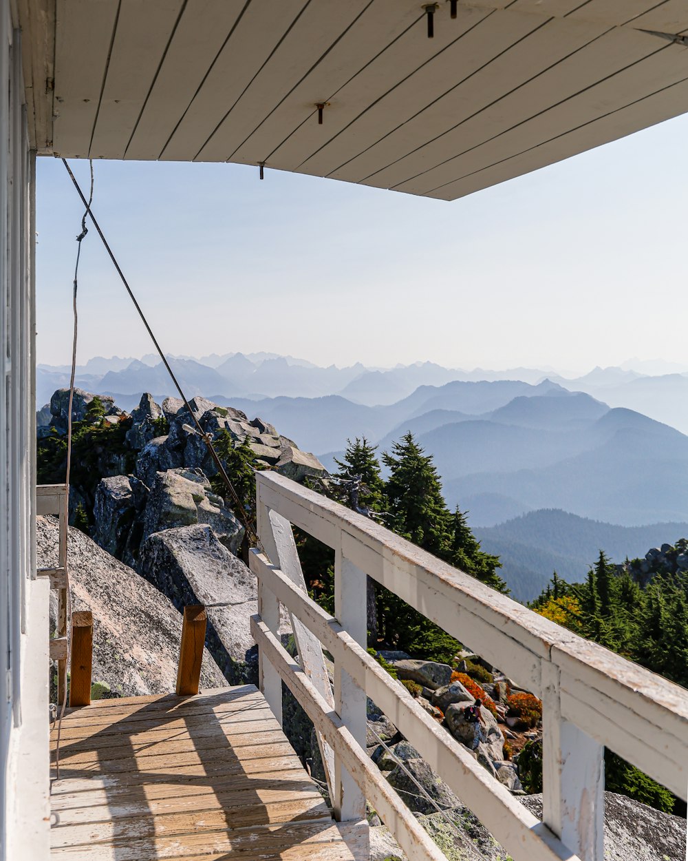 brown wooden deck near green trees and mountains during daytime