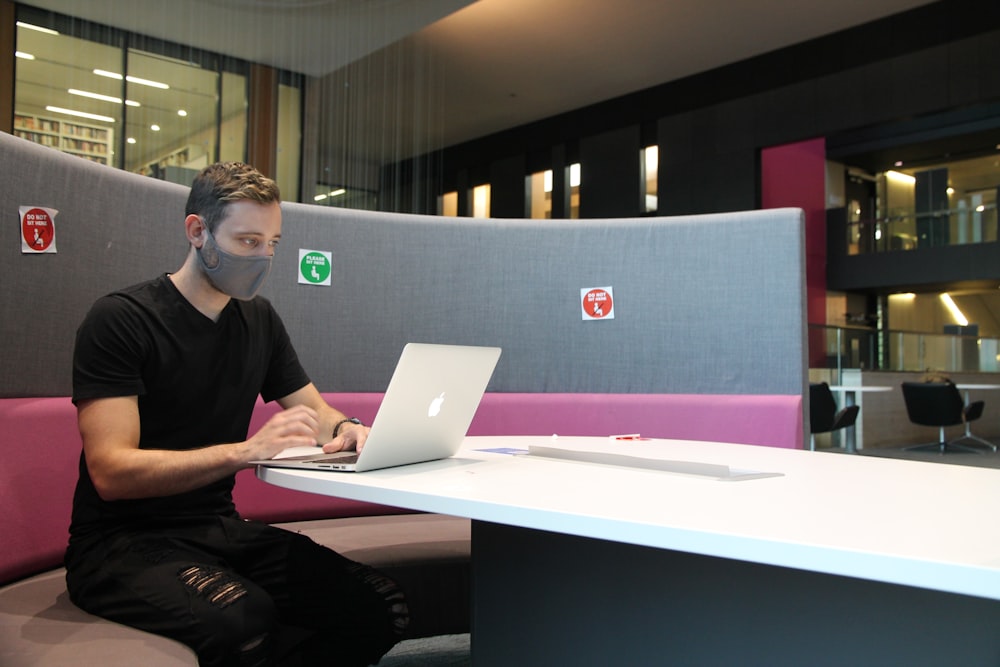 man in black polo shirt using macbook