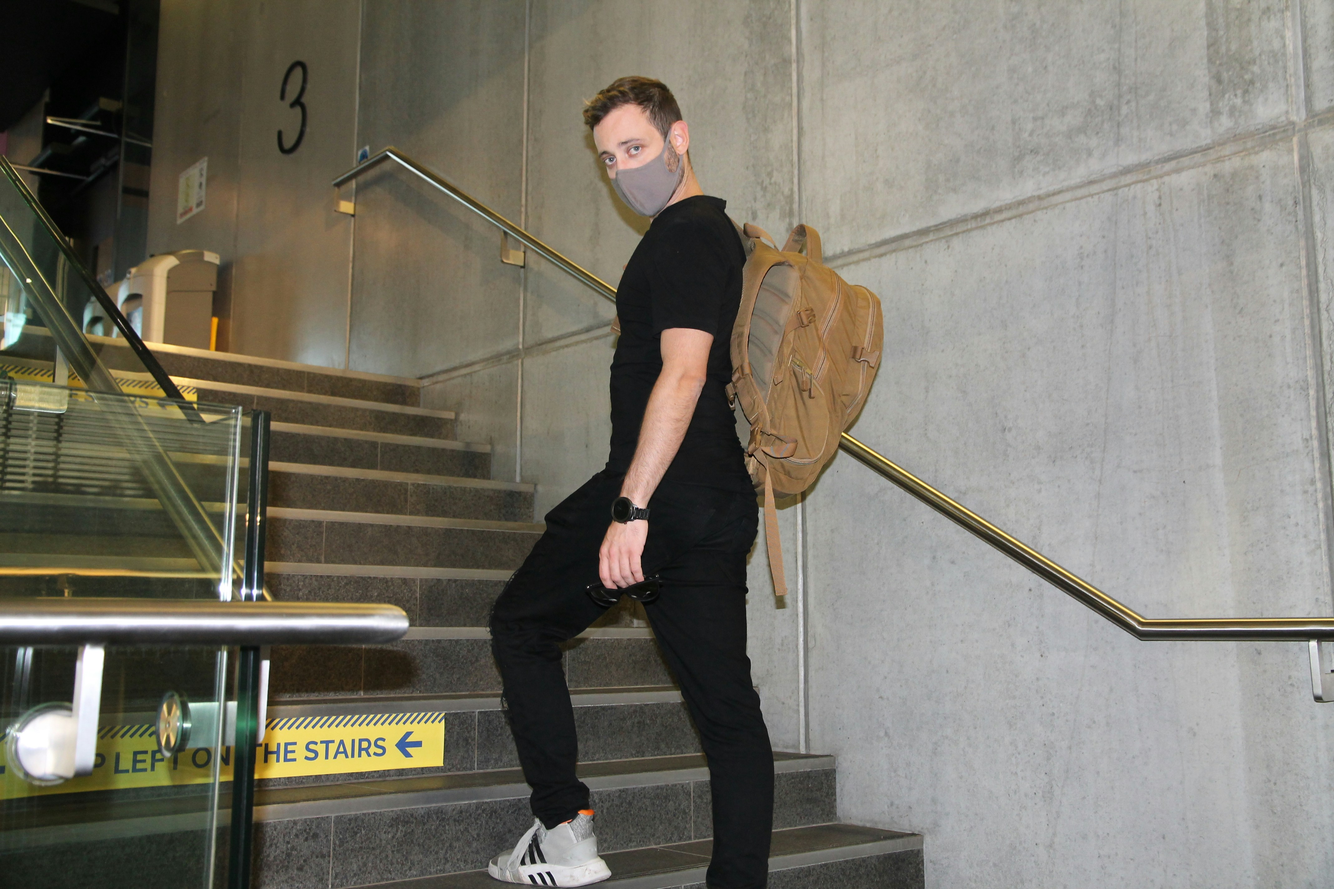 man in black t-shirt and black pants holding brown hat