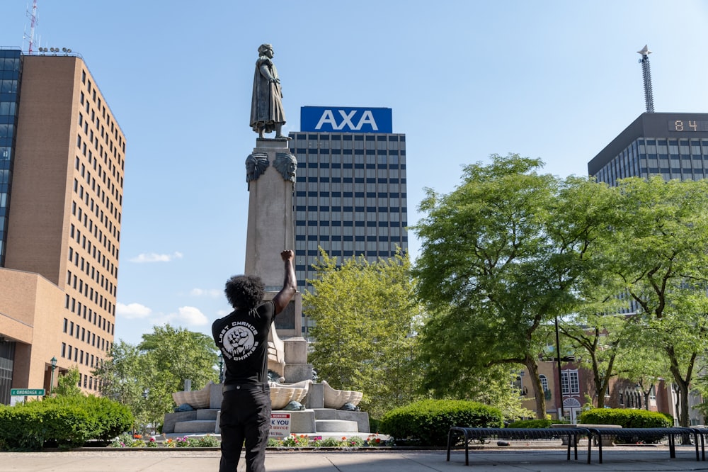 man in black and white long sleeve shirt and black pants standing near statue during daytime