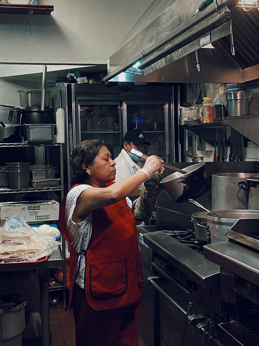 woman in red sleeveless dress holding stainless steel cooking pot