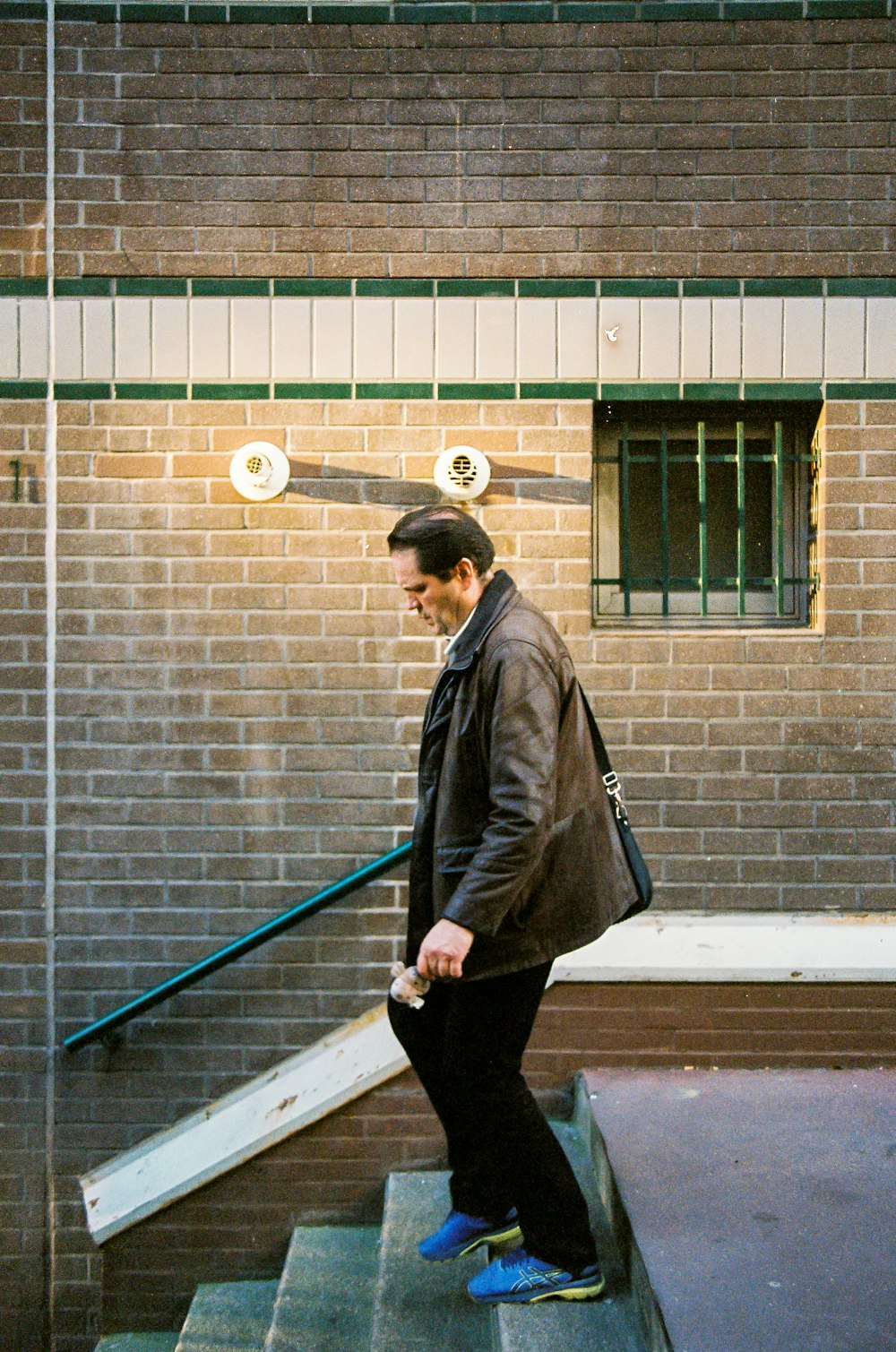 woman in black coat and black pants standing beside gray brick wall during daytime