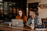 man and woman sitting in front of silver macbook