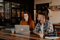 man and woman sitting in front of silver macbook