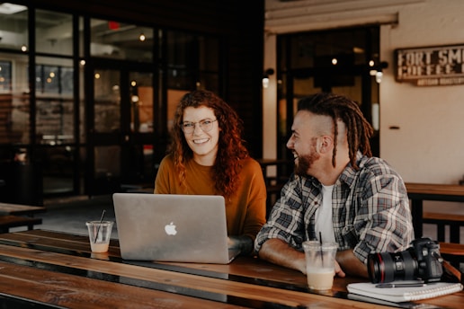 man and woman sitting in front of silver macbook