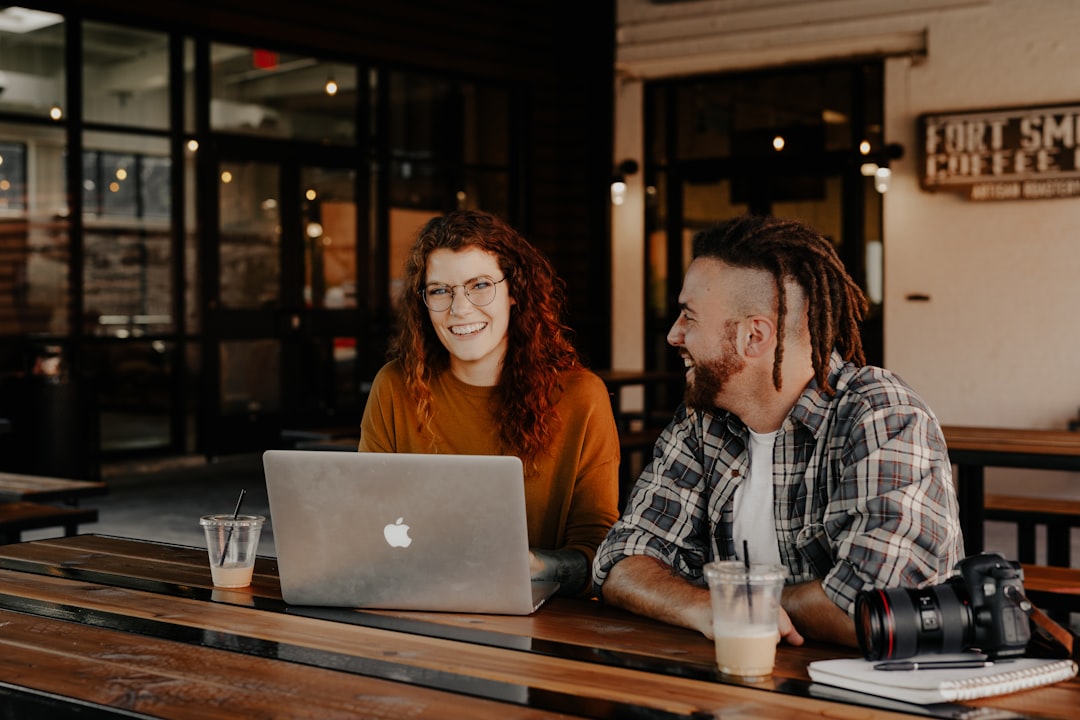 man and woman sitting in front of silver macbook,