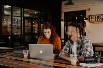 man and woman sitting at table using macbook