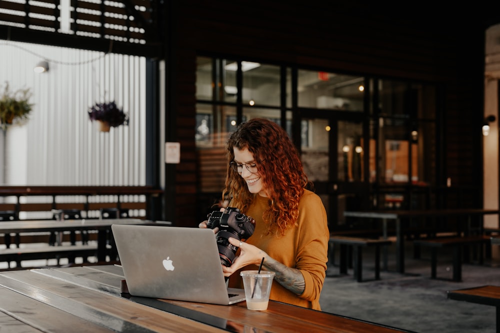 woman in brown long sleeve shirt using silver macbook