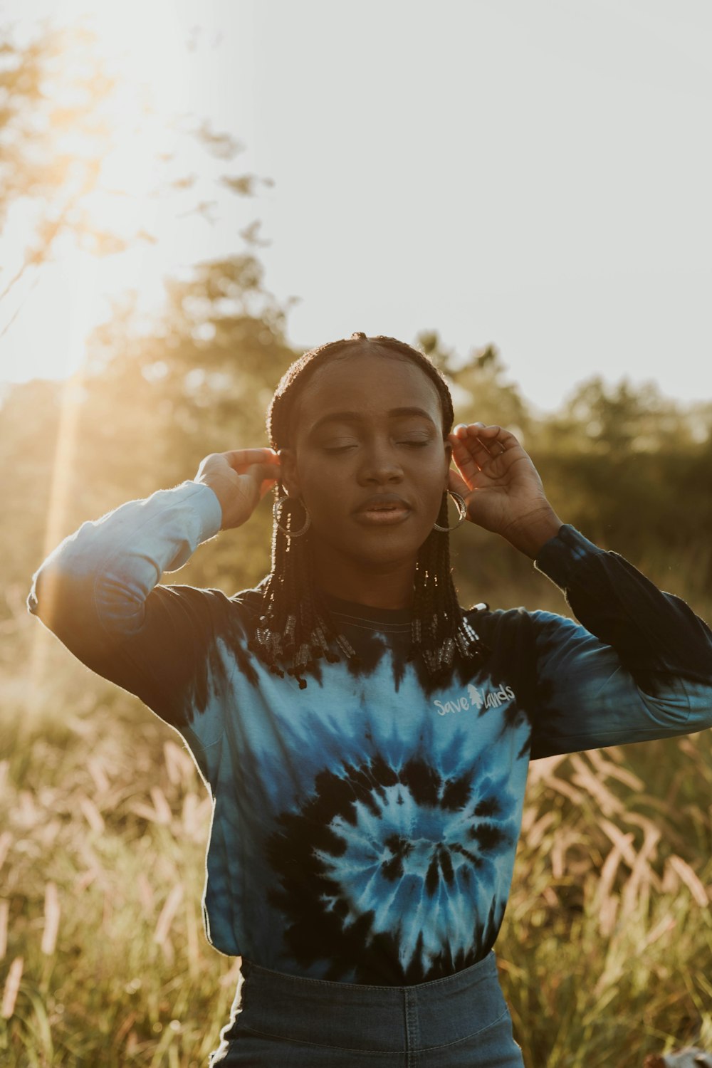 woman in blue and white crew neck t-shirt standing on brown grass field during daytime