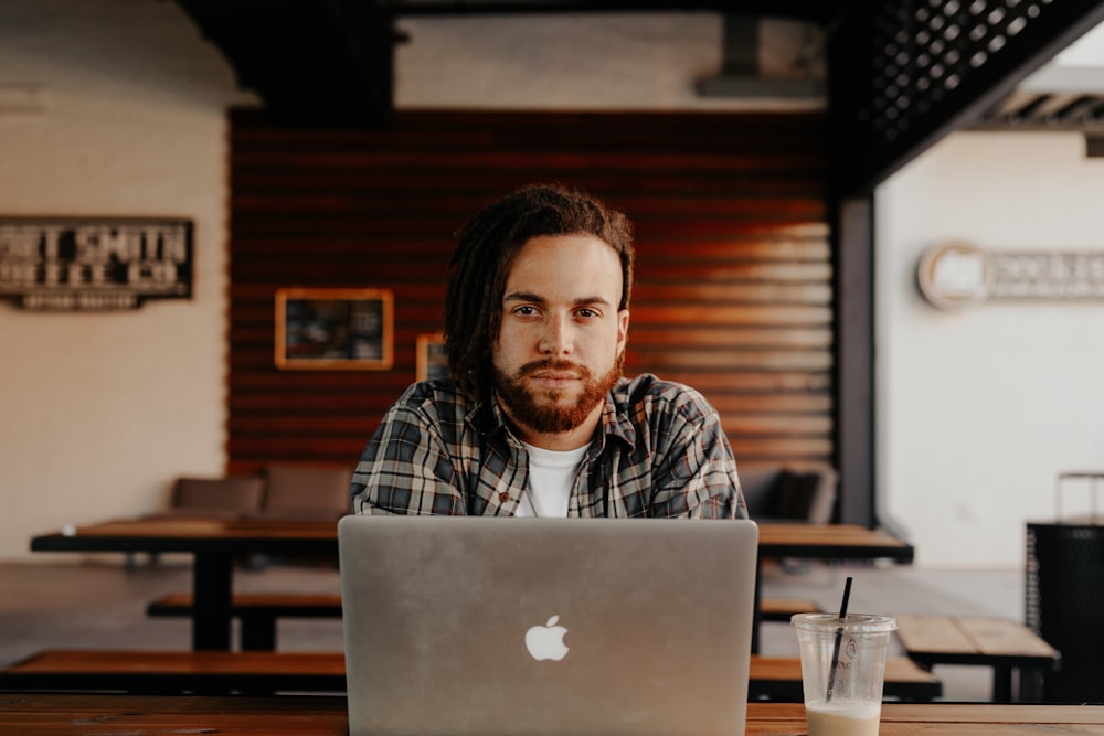 man in black and white plaid dress shirt using silver macbook