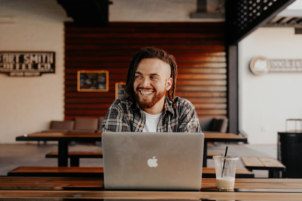 man in black and white plaid dress shirt using silver macbook