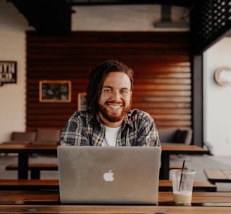 man in black and white striped polo shirt sitting on chair in front of silver macbook