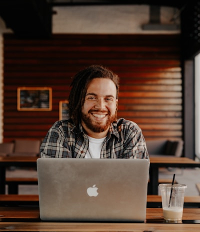 man in black and white striped polo shirt sitting on chair in front of silver macbook