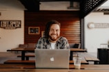 man in black and white striped polo shirt sitting on chair in front of silver macbook