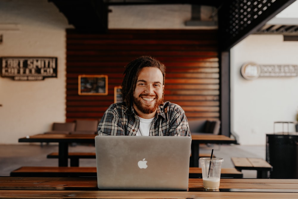 man in black and white striped polo shirt sitting on chair in front of silver macbook