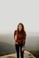 woman in brown long sleeve shirt and blue denim jeans standing on brown field during daytime