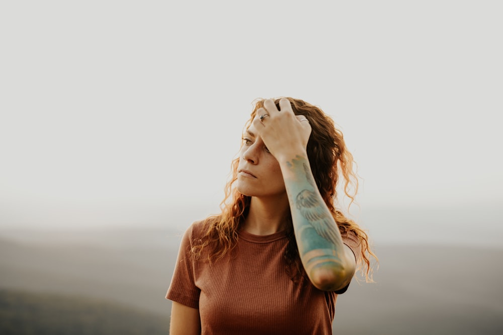 woman in brown crew neck t-shirt covering her face with her hands