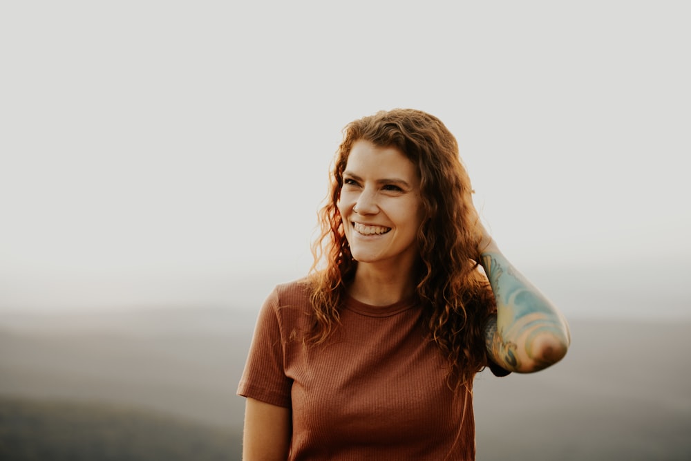 woman in brown crew neck t-shirt holding blue plastic bottle