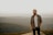 man in brown and white plaid button up shirt standing on brown rock during daytime