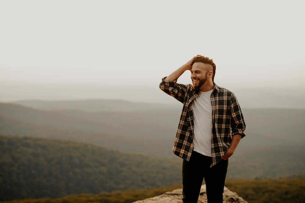 man in black and white plaid button up shirt standing on rock during daytime