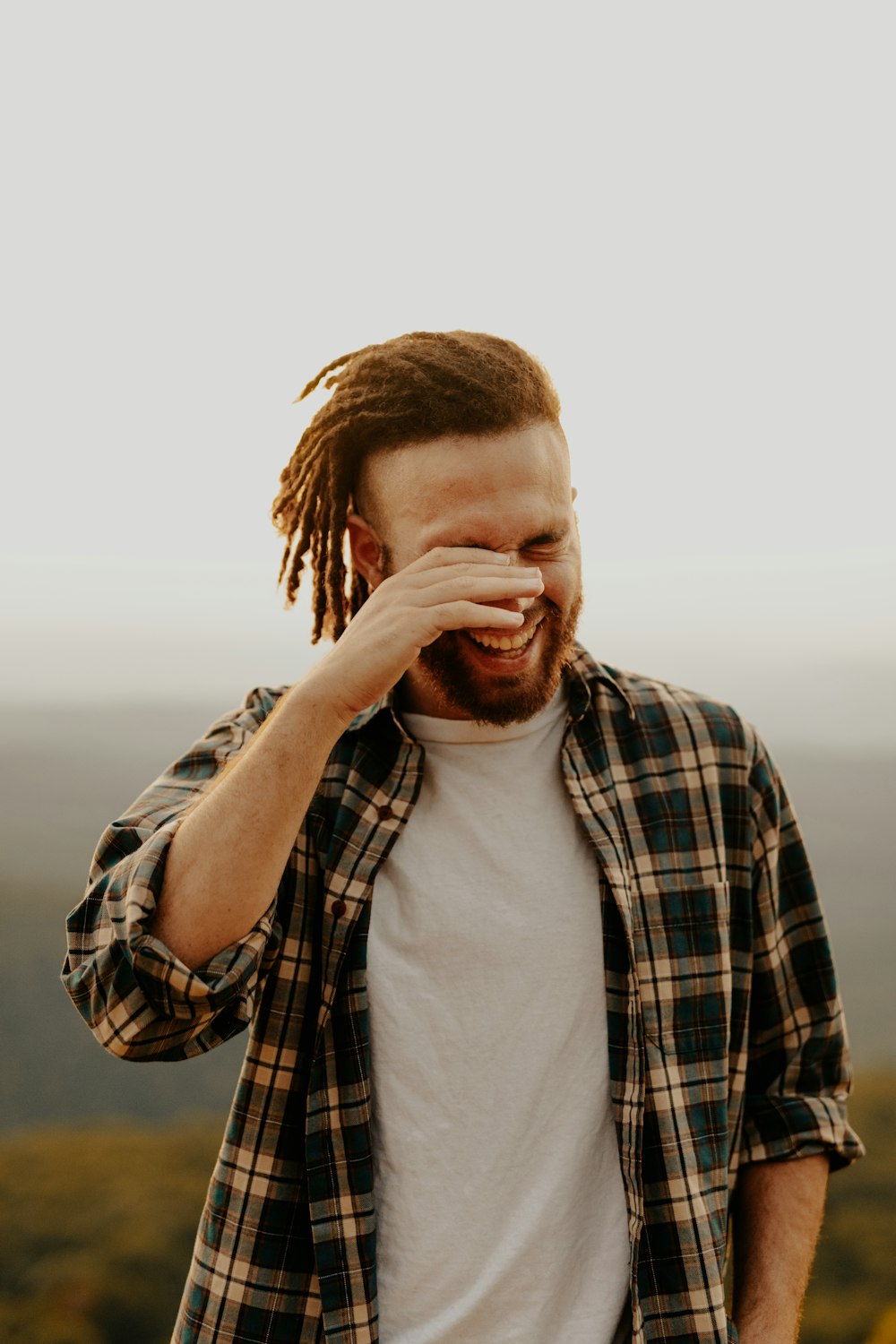 man in black and white plaid dress shirt covering his face with his hand