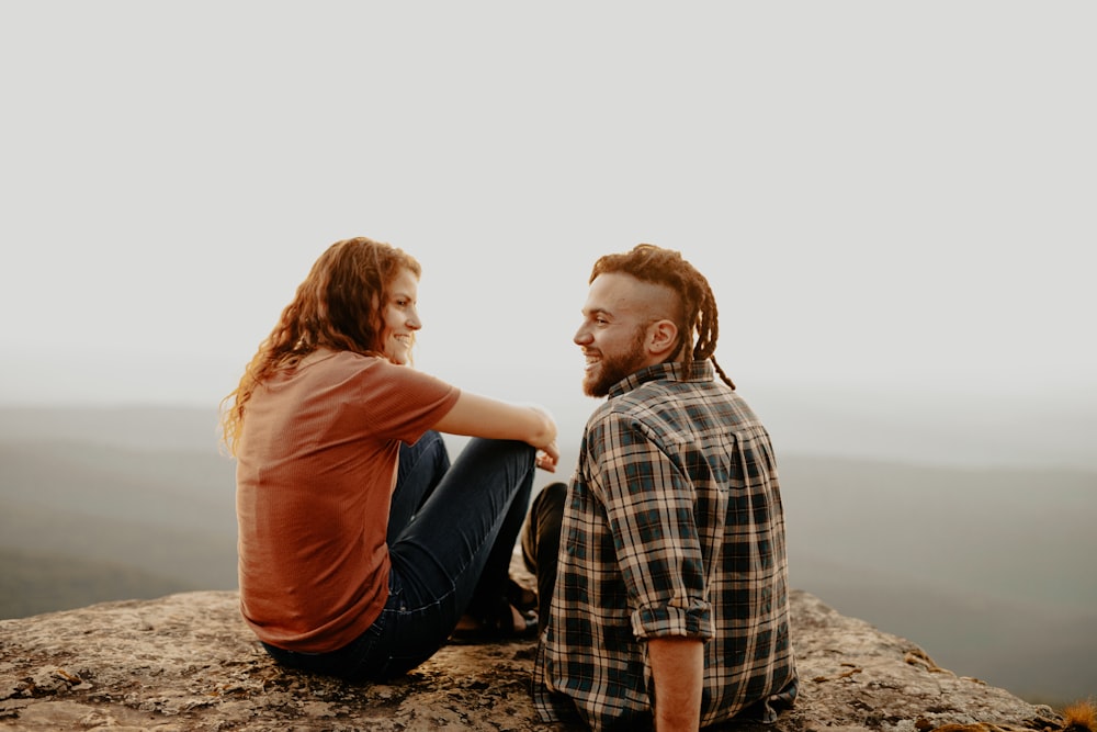 man and woman sitting on brown sand during daytime