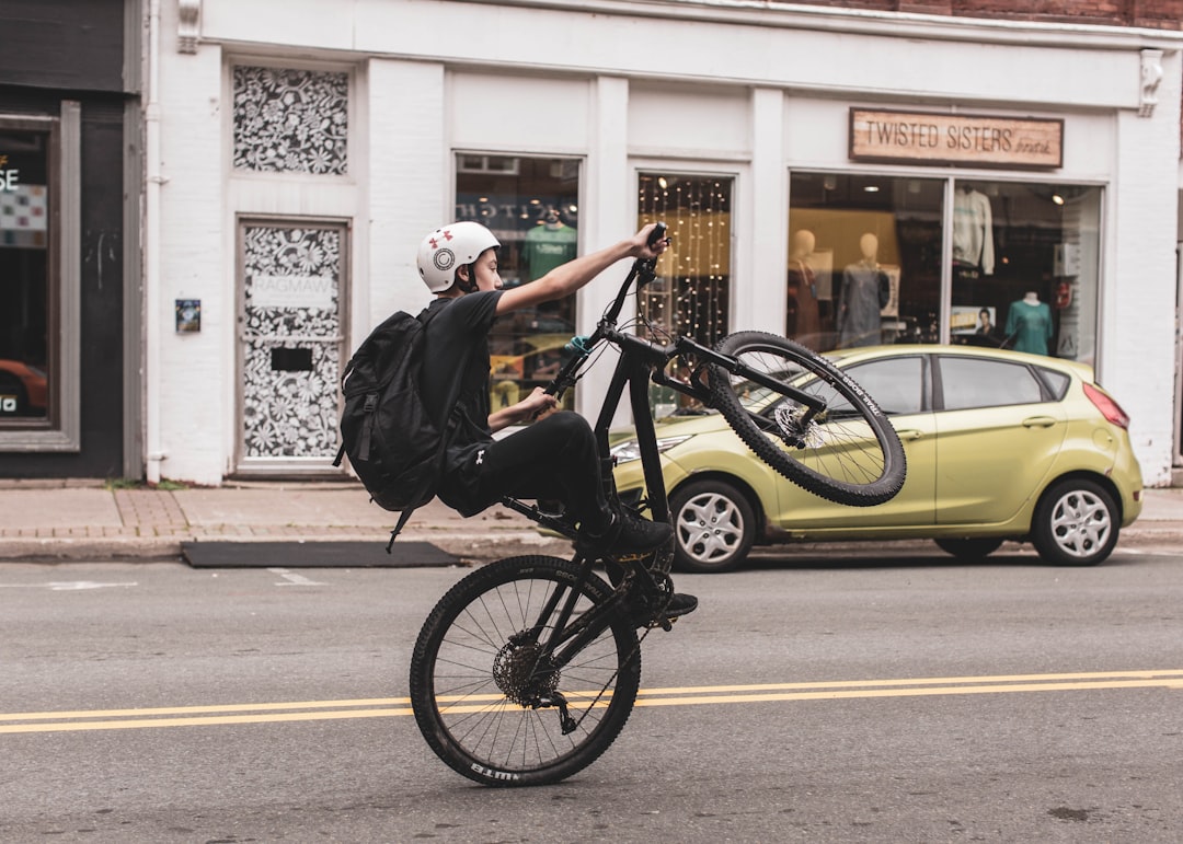 man in black jacket riding bicycle on road during daytime