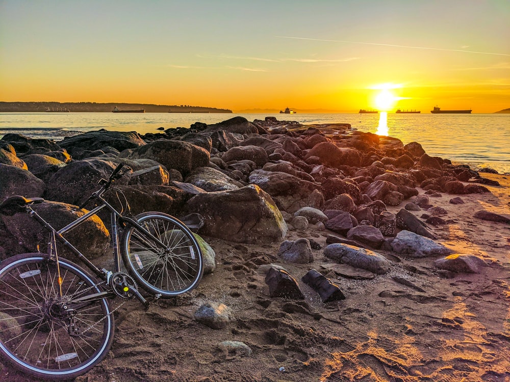 black bicycle on rocky shore during sunset