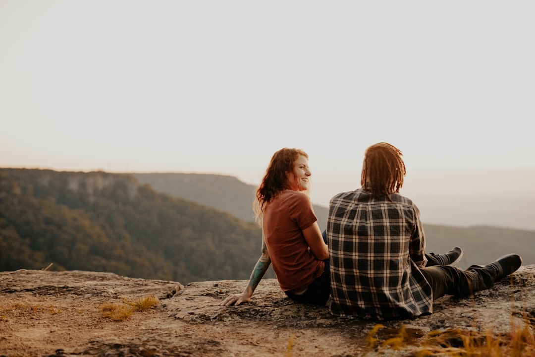 2 women sitting on rock during daytime