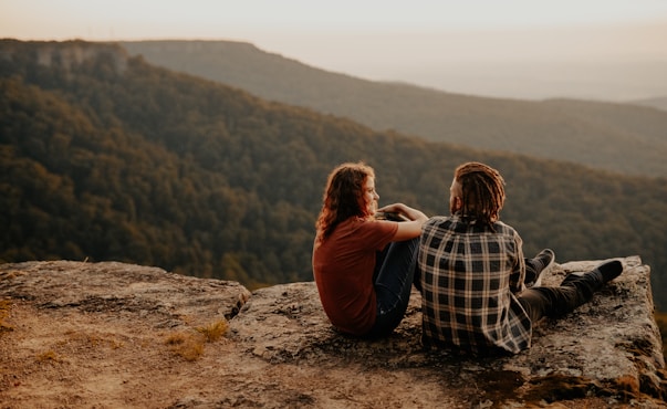 man and woman sitting on brown rock during daytime