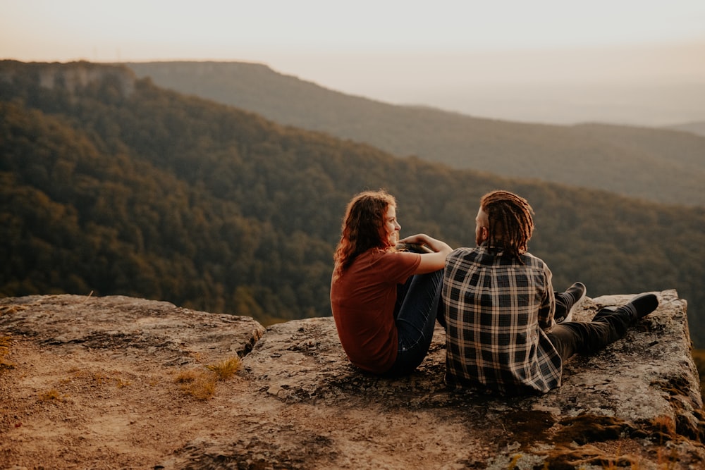 man and woman sitting on brown rock during daytime