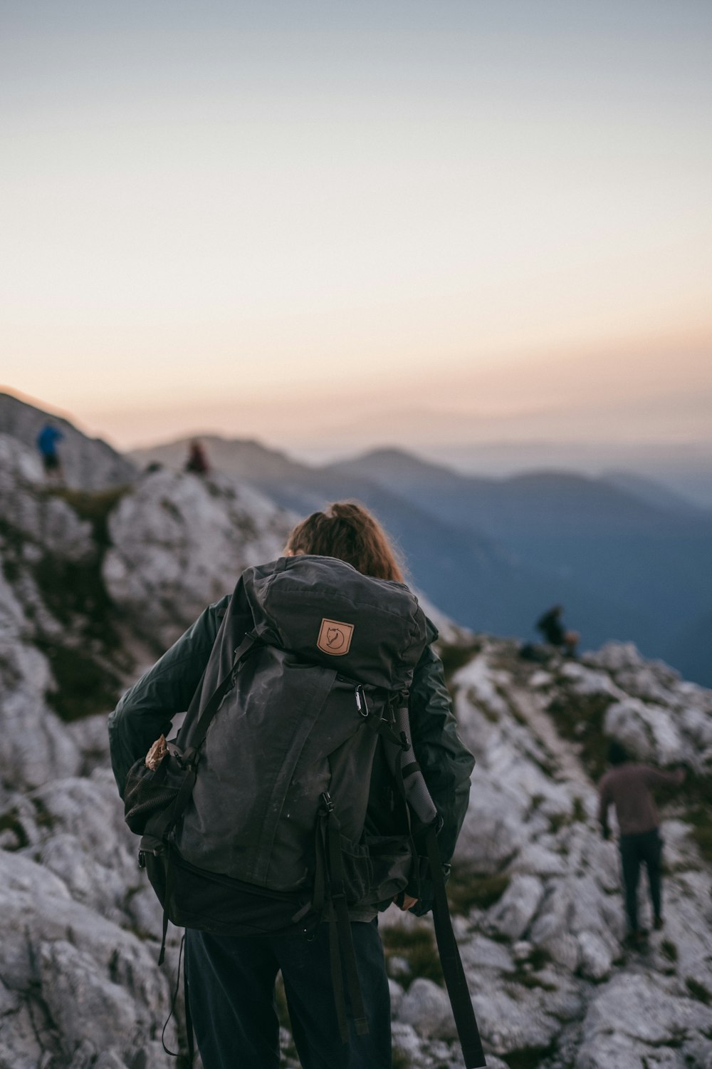 woman in black jacket with black backpack standing on mountain during daytime