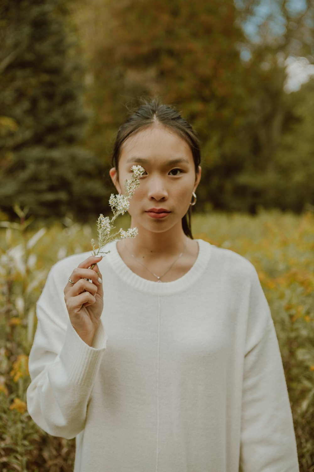 woman in white crew neck long sleeve shirt holding white flower