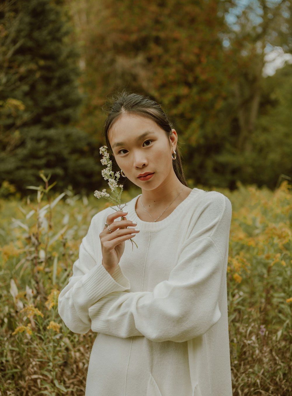 woman in white long sleeve shirt standing near green plants during daytime