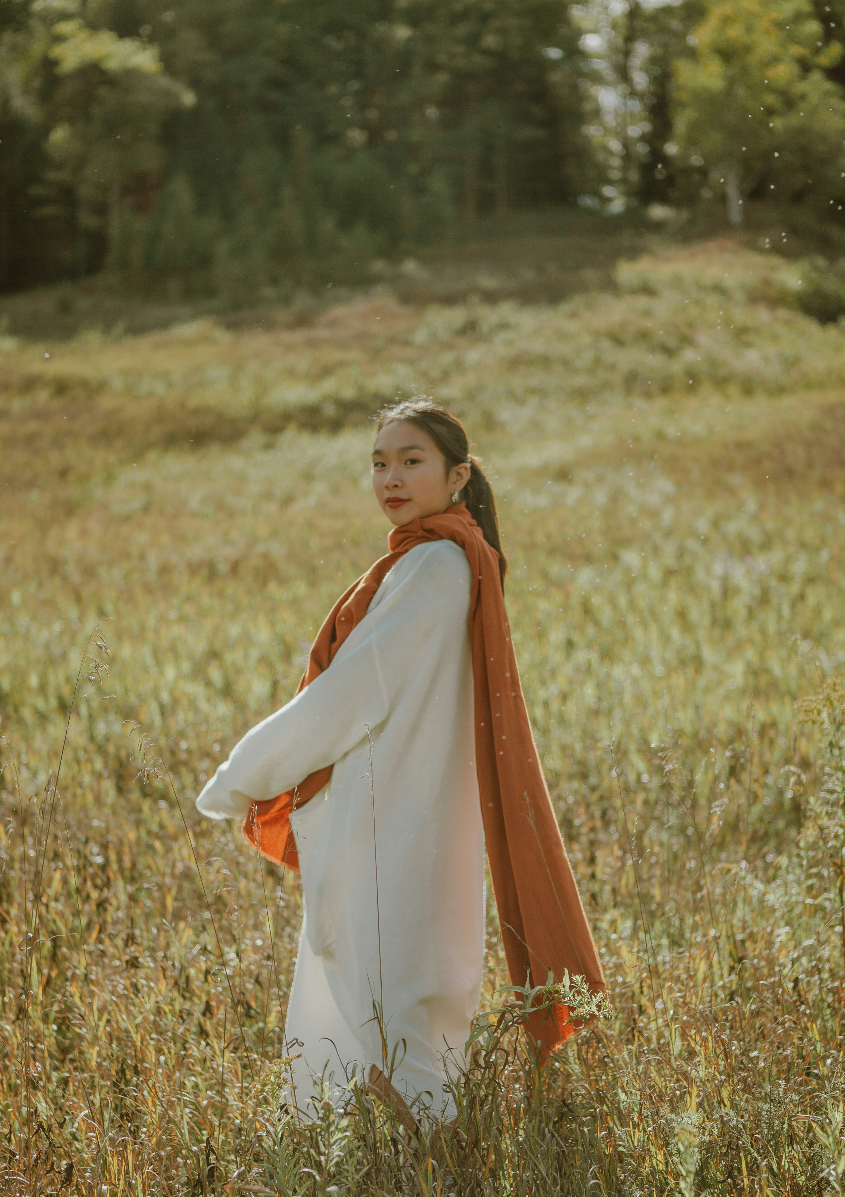 woman in orange dress standing on brown grass field during daytime