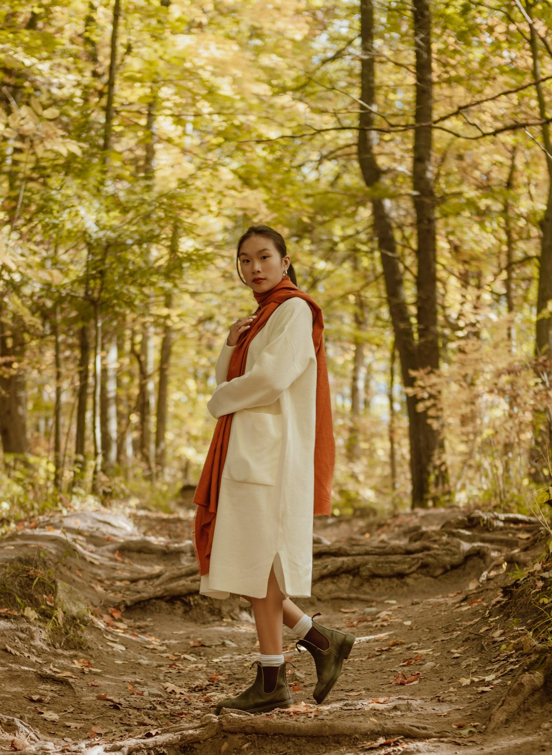 woman in white long sleeve dress standing on brown tree log during daytime