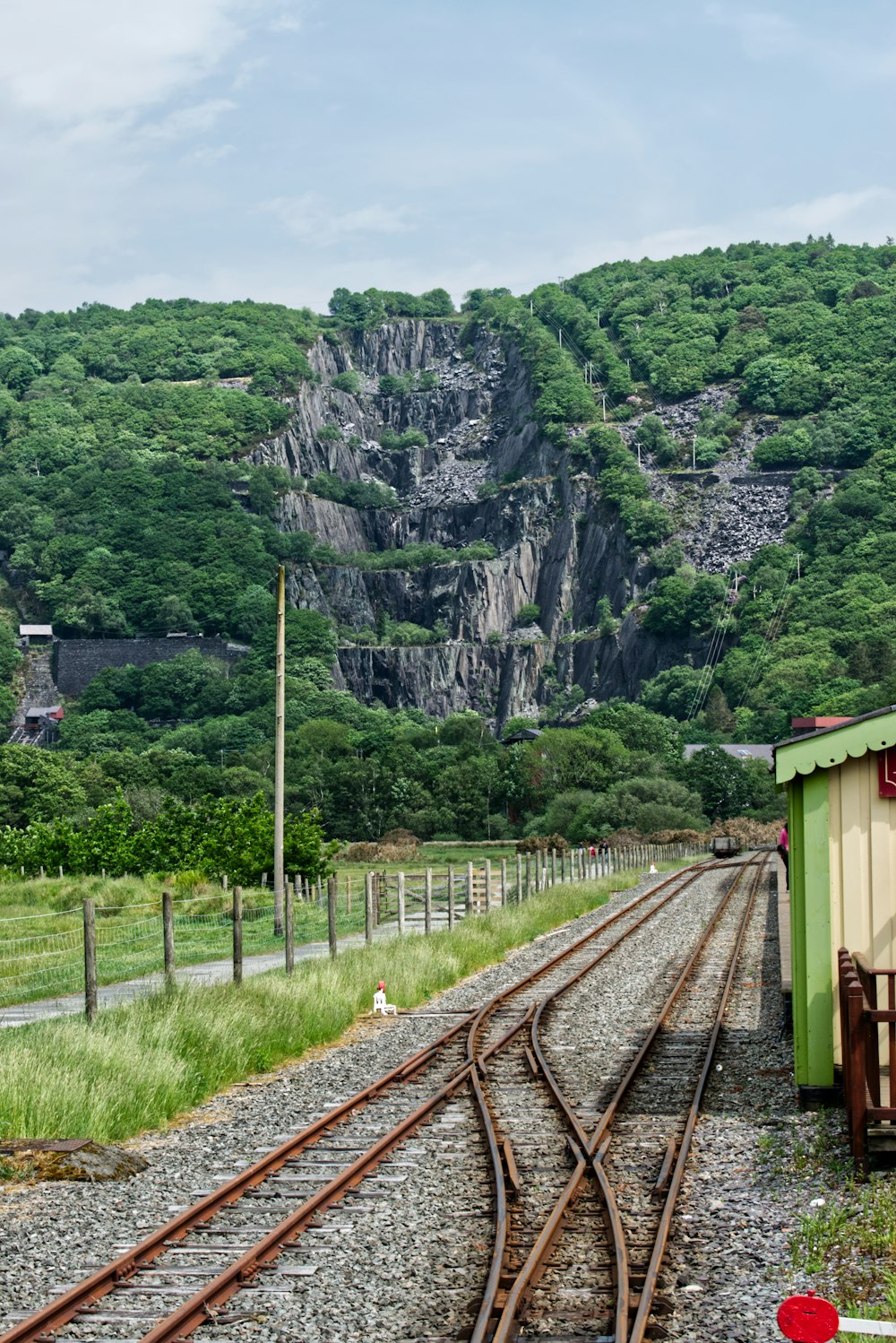 brown train rail near green trees and mountain during daytime